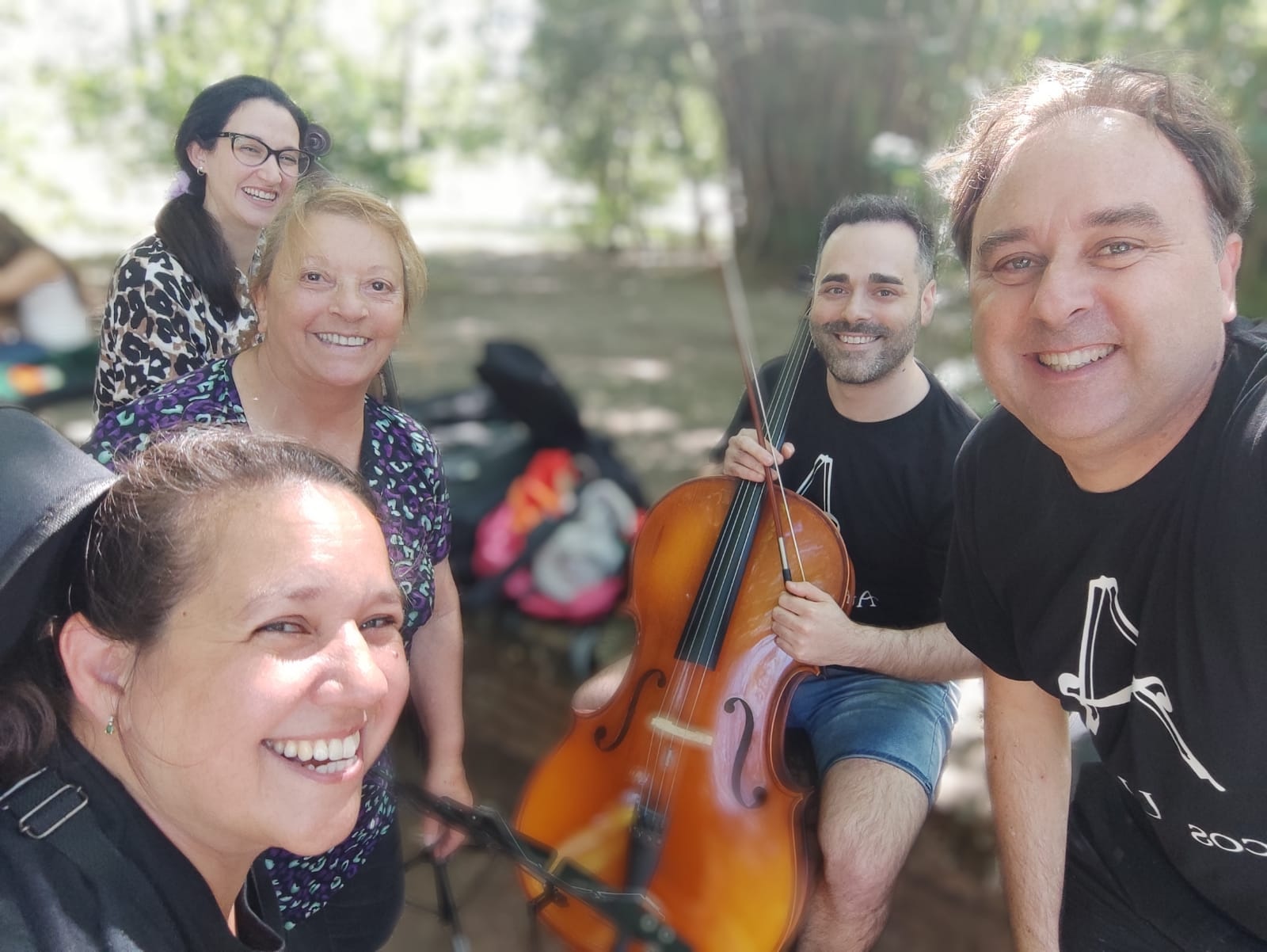 Profesores y estudiantes de Arcos Unidos con cello al aire libre