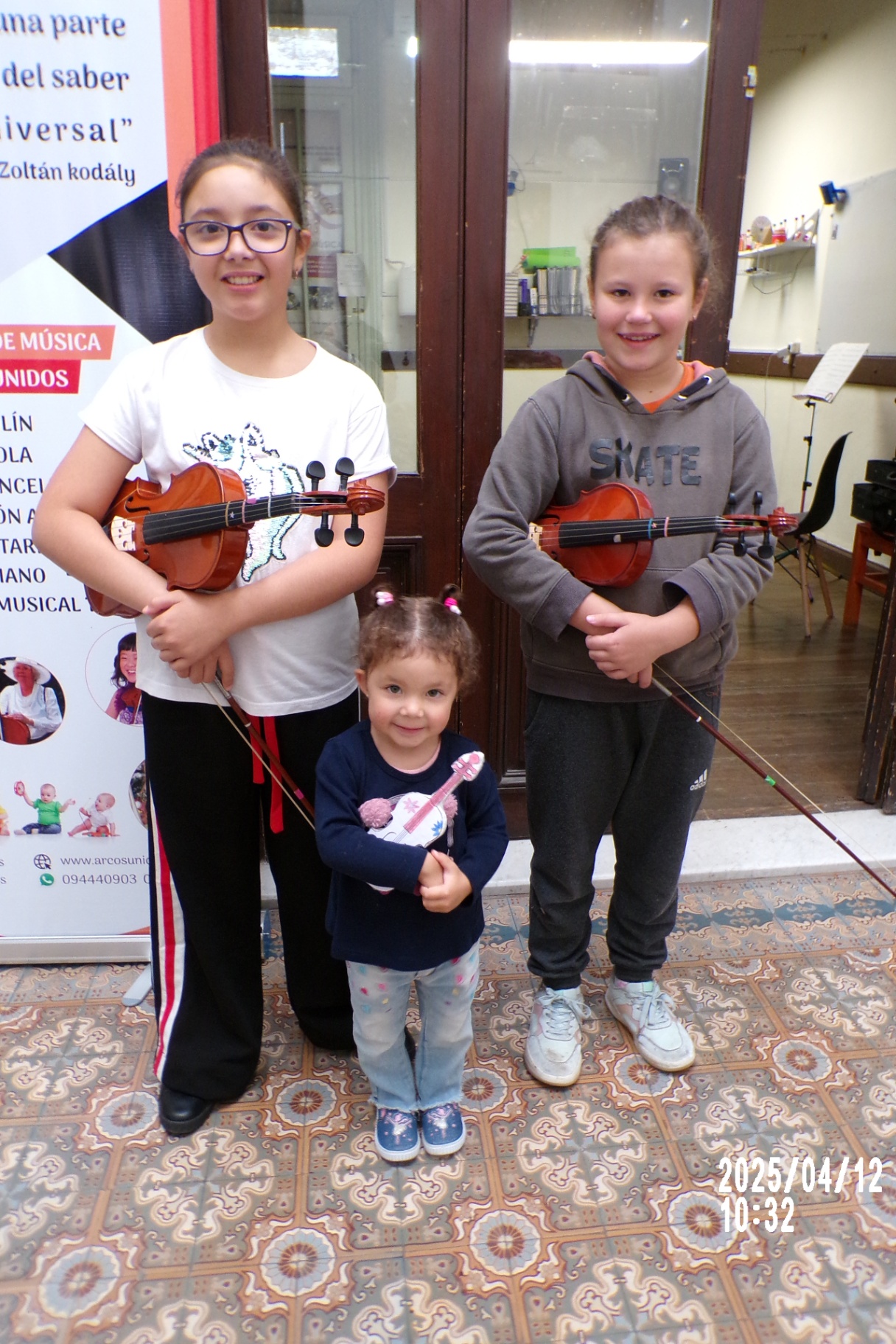 Tres pequeñas alumnas de violín en la academia Arcos Unidos
