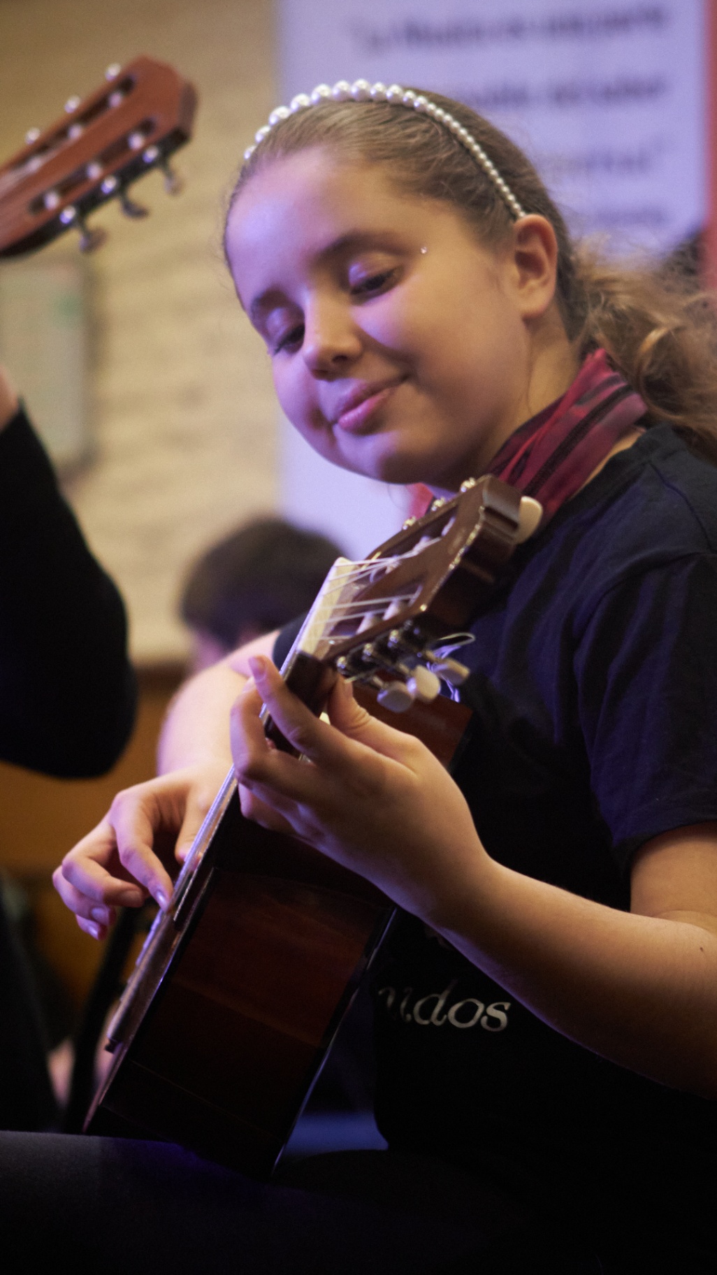 Alumna sonriente tocando la guitarra en concierto