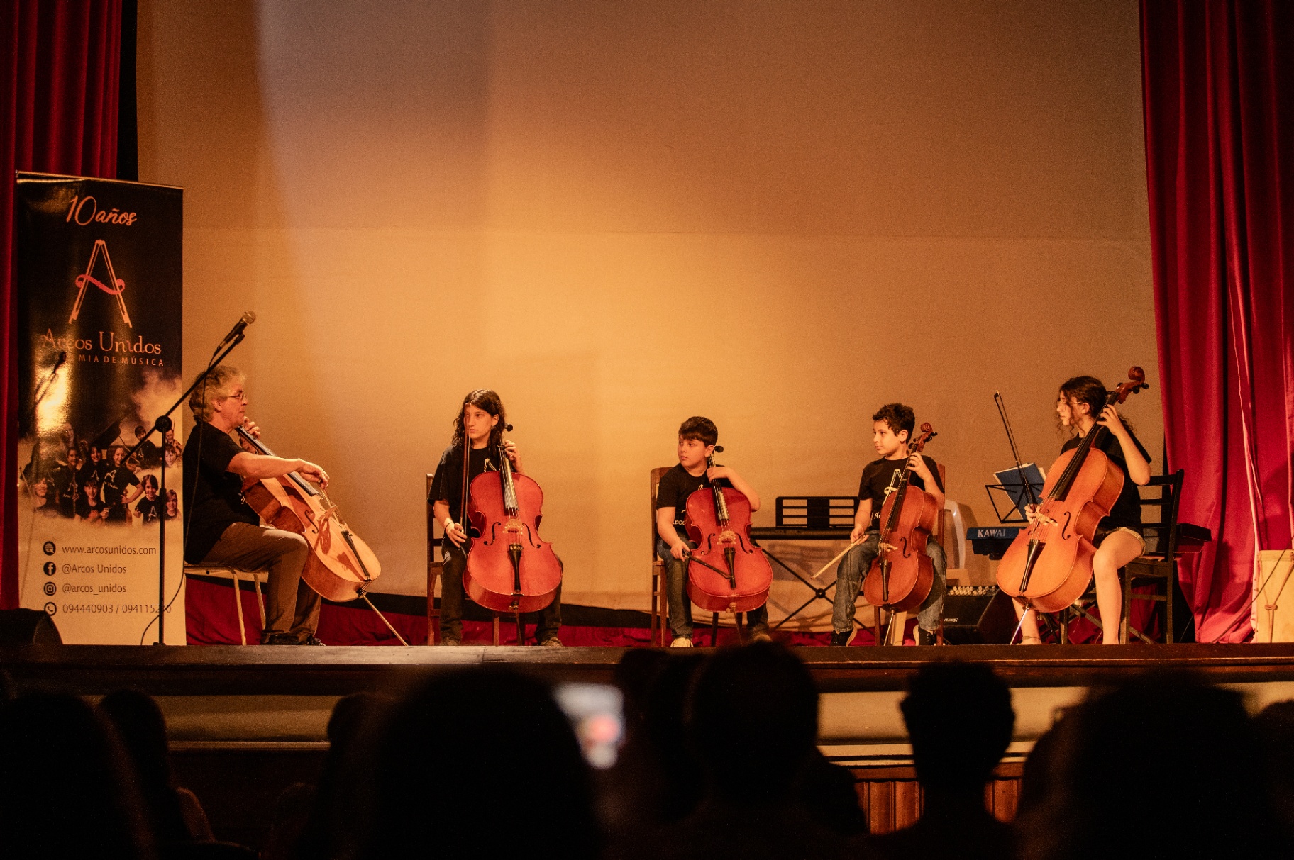 Maestro y estudiantes de violonchelo en concierto