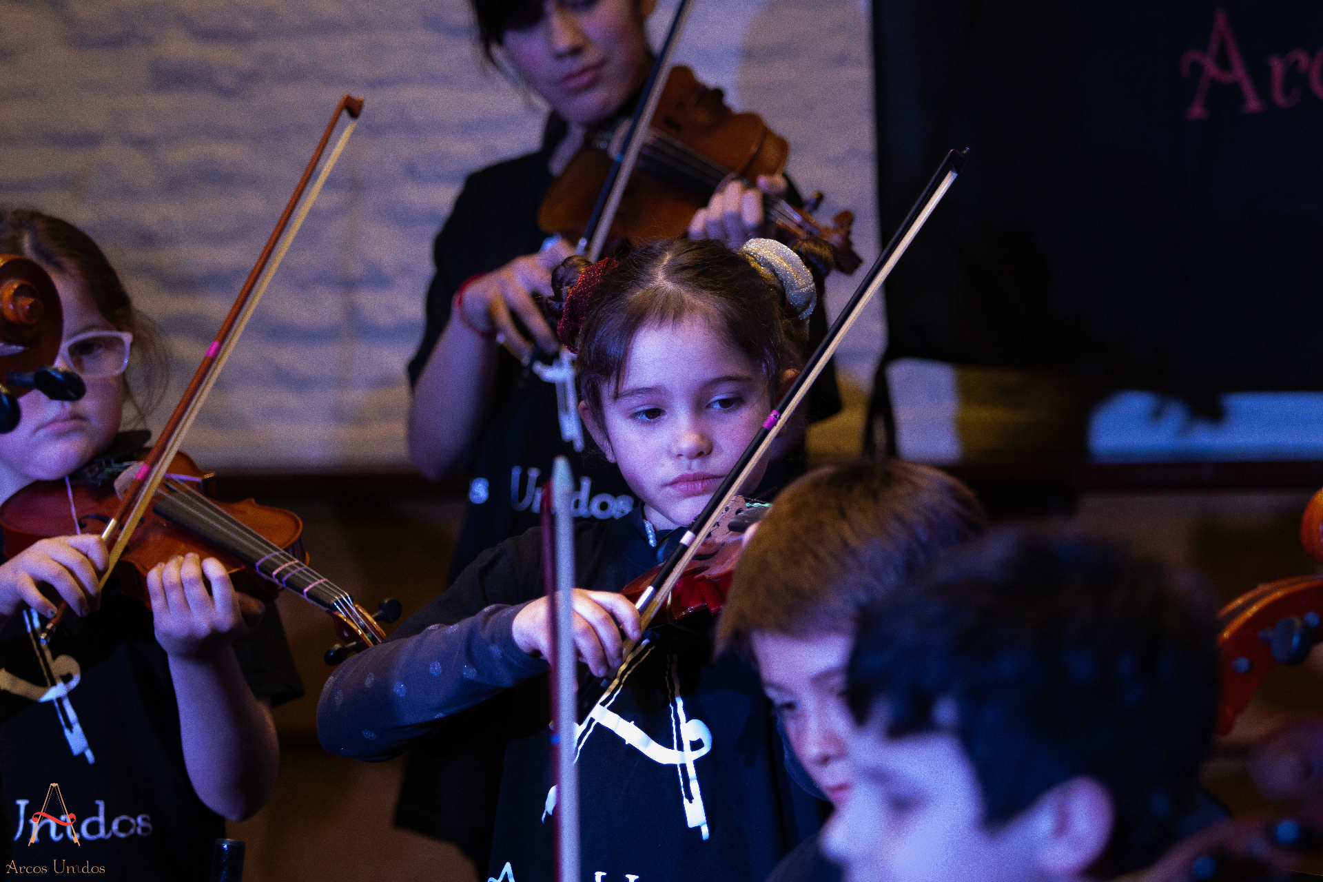Alumnas de Arcos Unidos tocando violín en concierto